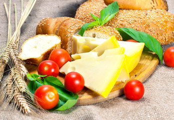 Cherry tomatoes cheese and cereal bread on cutting board.
