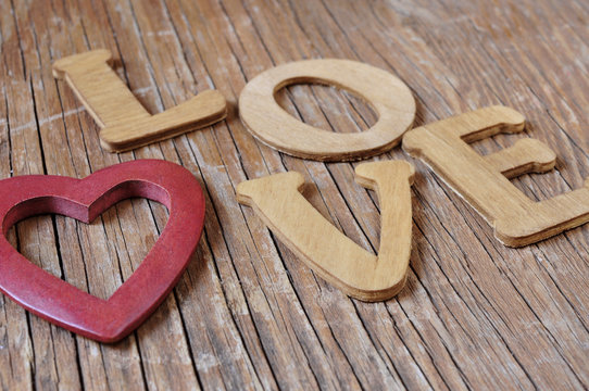 heart and letters forming the word love on a wooden surface
