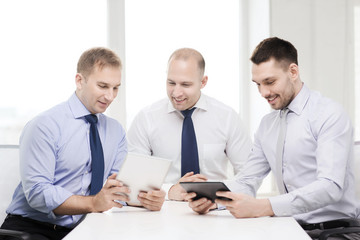 three smiling businessmen with tablet pc in office