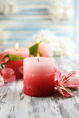Beautiful candles with flowers on wooden background