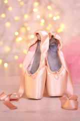 Ballet pointe shoes on floor on bokeh background