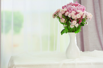 Beautiful flowers in vase with light from window