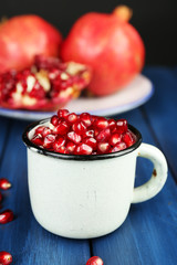 Juicy ripe pomegranate on wooden table, on dark background