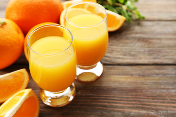 Glass of orange juice and slices on wooden table background