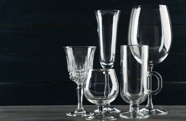 Empty glass goblets on dark color wooden background