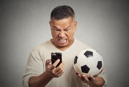 frustrated man looking on smartphone watching football game 