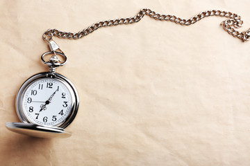 Silver pocket clock on old paper background