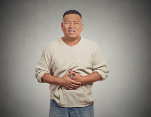 Man with stomach pain isolated on grey wall background 