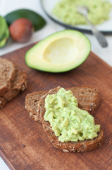 avocado dip (guacamaole) on bread on cutting board
