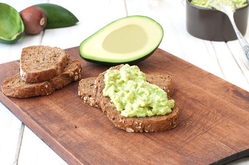 avocado dip (guacamole) on bread on cutting board