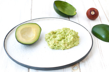 avocado dip (guacamaole) and avocado on a white plate