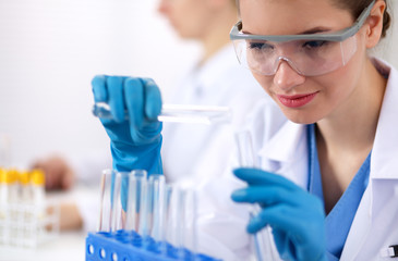 Fototapeta premium Woman researcher is surrounded by medical vials and flasks,