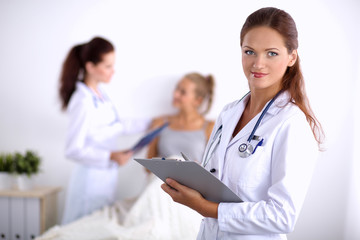 Fototapeta premium Smiling female doctor with a folder in uniform standing at