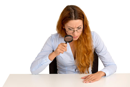 woman with glasses looking through magnifying glass