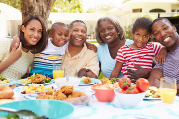Multi Generation Family Enjoying Meal In Garden Together