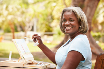 Senior Woman Sitting At Outdoor Table Painting Landscape