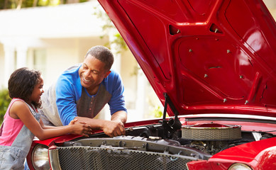 Grandfather And Granddaughter Working On Restored Car