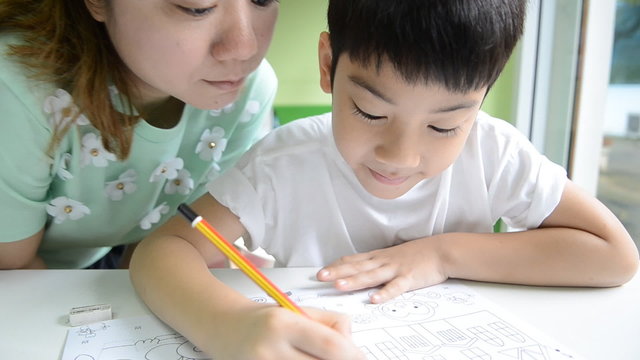 Asian Mom is helping her son to do homework of the school