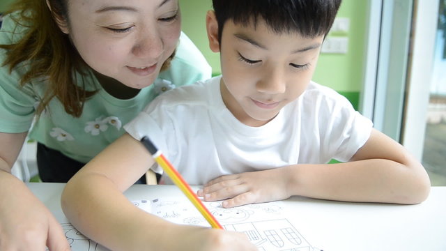 Asian Mom is helping her son to do homework of the school