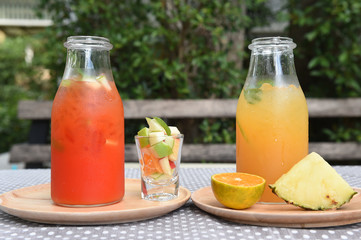 different bottles of juice with fruits on wooden table