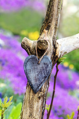 Altes Herz aus Holz mit lila Blaukissen im Hintergrund