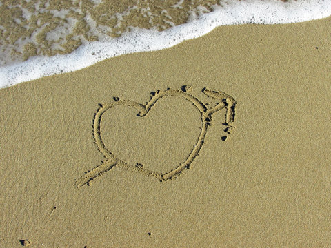 Heart pierced by an arrow drawn in the sand
