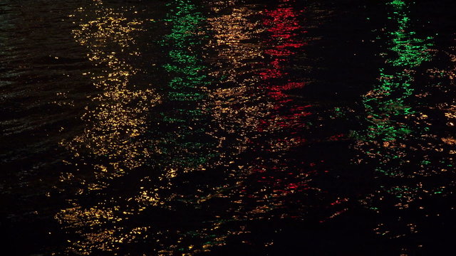 Reflections of coloured lights in the night the river. 4K.