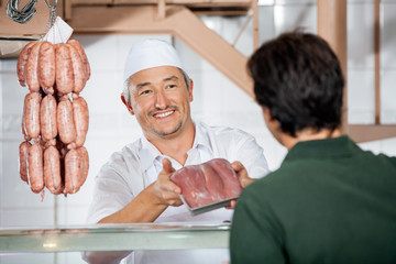 Butcher Showing Packed Sausages To Customer