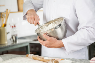 Chef Mixing Batter With Wire Whisk In Bowl In Kitchen