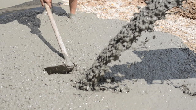 Construction workers pour concrete mix from cement mixer.