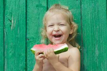 Two-year-girl laughing and holding watermelon