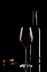 Glass of red wine, bottle and corkscrew