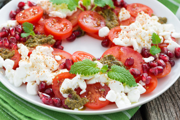 fresh salad with tomatoes, cottage cheese, pesto and pomegranate