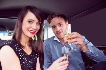 Happy couple drinking champagne in limousine