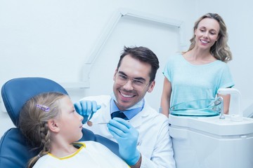 Fototapeta premium Dentist examining girls teeth with assistant