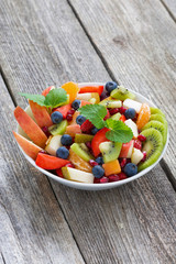 Fruit and berry salad on wooden table, vertical