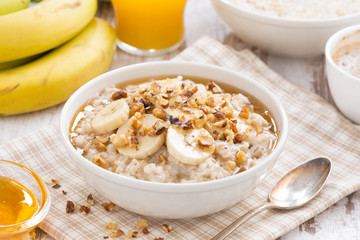 oatmeal with banana, honey and walnuts for breakfast - obrazy, fototapety, plakaty