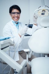 Smiling female dentist holding dental tool