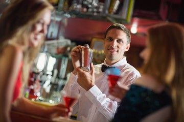 Handsome barman smiling at camera making a cocktail