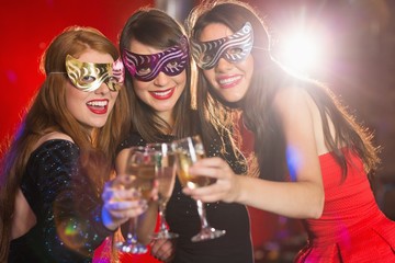 Friends in masquerade masks toasting with champagne - obrazy, fototapety, plakaty