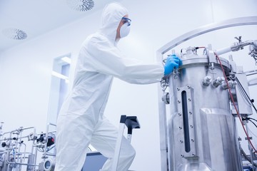 Scientist in protective suit standing on ladder