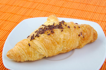 Croissant with chocolate on wooden background. Breakfast.