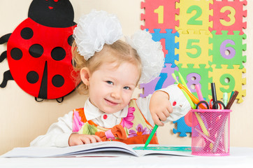 Cute child girl drawing with pencils iin kindergarten