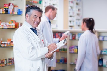 Obraz premium Smiling pharmacist in lab coat writing a prescription