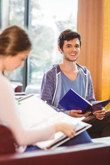 Students sitting on couch revising and smiling at camera