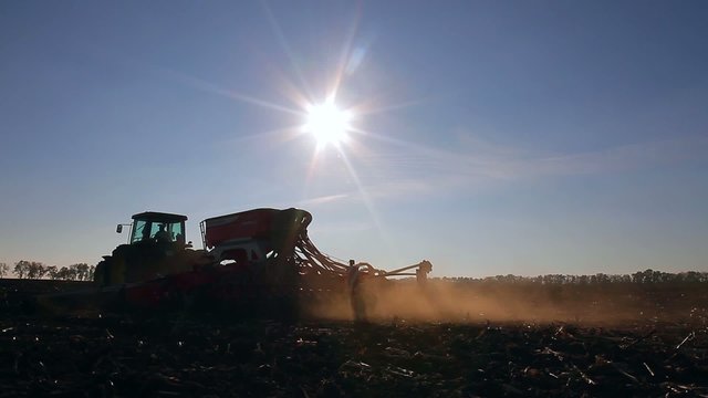 tractor goes across the field and raises dust