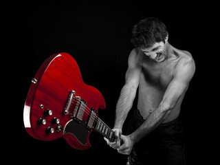 Angry man breaks a guitar.