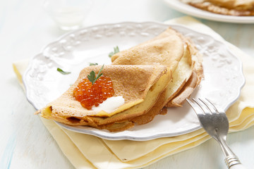 Pancakes with caviar, sour cream and parsley