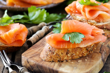 Smoked salmon canape with parsley leaf on rustic wood