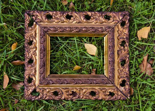 antigue  picture frame on autumn grass with yellow leaves